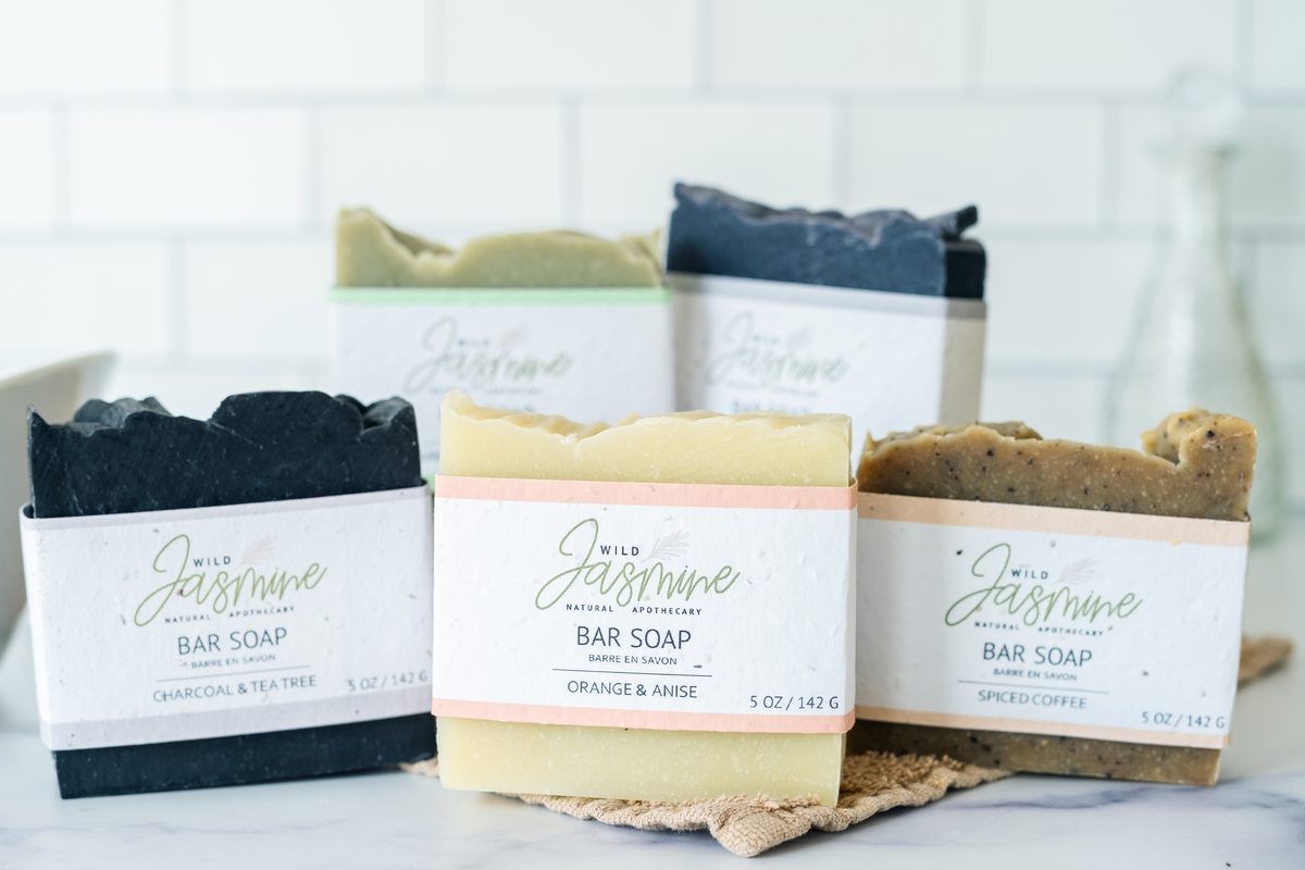 Five bars of handmade Wild Jasmine soap arranged on a marble counter in front of a white tile wall.