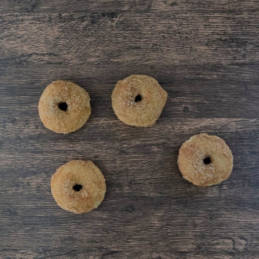 Middle frame of the same sequence: the donuts have shifted positions across the dark wood surface.