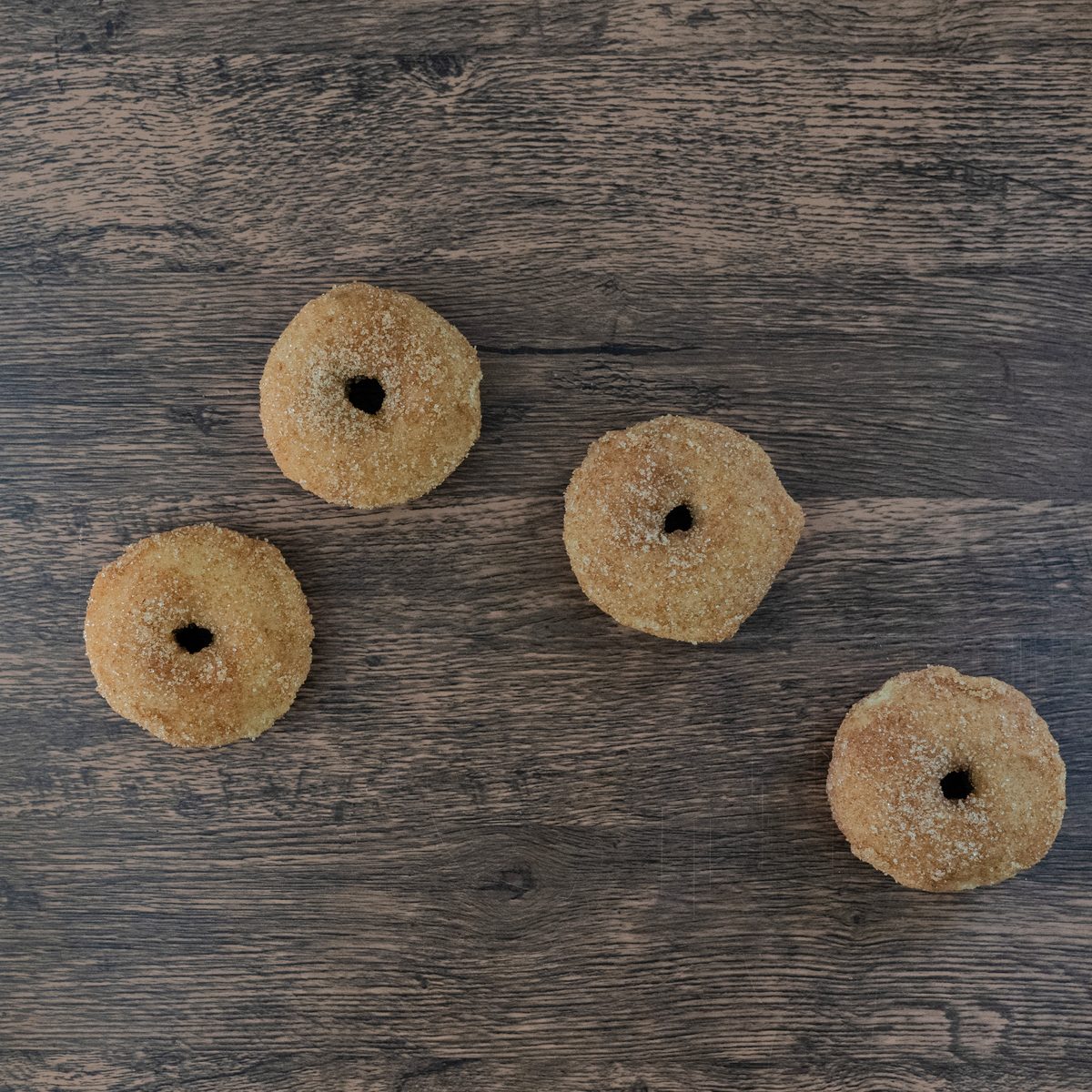 Final frame of the sequence: the donuts have moved again into a new arrangement on the dark wood.
